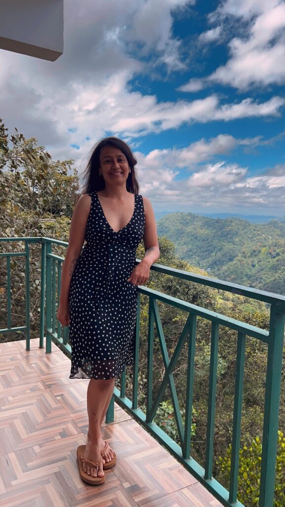 Reshma standing on the balcony of her Deluxe room at Lazo Golden Valley Resort, Munnar